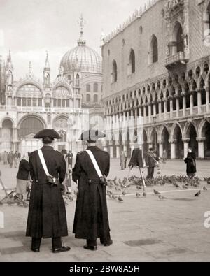 ANNÉES 1930 DEUX MEMBRES DE L'ARMA DEI CARABINIERI EN UNIFORME HISTORIQUE DEBOUT SUR LA PIAZZA SAN MARCO PRÈS DU PALAIS DES DOGES VENISE ITALIE - R5116 HAR001 HARS PRÈS DE OCCUPATIONS PALACE UNIFORMES MEMBRES ÉLÉGANTS DEI OFFICIERS COPS DOGE INI HOMME MOYEN-ADULTE PIGEONS BADGE BADGES NOIR ET BLANC HAR001 MARCO OLD FASHION POLICIER PLACE Banque D'Images