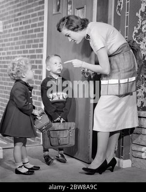 UNE MÈRE DES ANNÉES 1950 SE SECOUANT LE DOIGT PARLANT À UN GARÇON ET UNE FILLE À LA PORTE AVANT QUE LES ENFANTS NE PARTENT À L'ÉCOLE EN DONNANT DES INSTRUCTIONS DE SÉCURITÉ - S6483 HAR001 HARS DONNER À DES JEUNES COMMUNICATION DE STYLE ÉLÉMENTAIRE JEUNES ADULTES INFORMATIONS DE SÉCURITÉ FILS FAMILLES POINT DE VIE FEMMES FRÈRES MAISON VIE COPIE ESPACE FEMMES FILLES PLEINE LONGUEUR PERSONNES DISCIPLINE HOMMES LES SŒURS À RISQUE QUITTENT LES ÉCOLES B&W AVANT LA MATERNELLE, NIVEAU ÉLEVÉ, PROTECTION DE L'AVENTURE AVERTISSEMENT DIRECTION DE L'AUTORITÉ PRINCIPALE SŒUR INSTRUISANT DES INSTRUCTIONS CONCEPTUELLES COOPÉRATION ÉLÉGANTE ÉCOLE INDICE DE CROISSANCE FINGER MINEURS Banque D'Images