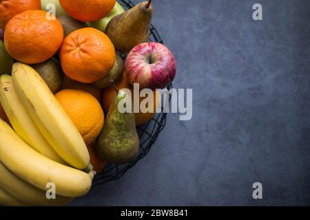 Variété de fruits tels que les pommes, les bananes, les poires et les oranges sur un fruiterer sur fond de béton. Une alimentation saine. Vue de dessus. Espace de copie côté droit. Banque D'Images