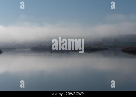 Paysage de rivière brouillard au lever du soleil avec de faibles nuages et réflexion sur l'eau à Alcacer do Sal, Portugal Banque D'Images