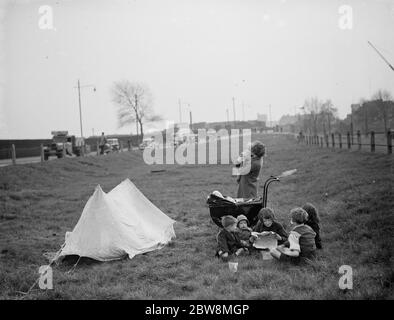 Les enfants ont un pique-nique sur un peu d'herbe à côté de la route. 1938 Banque D'Images