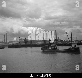 Vue sur la rivière montrant les navires et les usines de la Tamise. La fumée est vue biloquant hors des cheminées d'usine . 1936 Banque D'Images