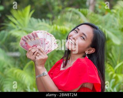 L'argent indonésien entre les mains d'une fille asiatique. Banque D'Images