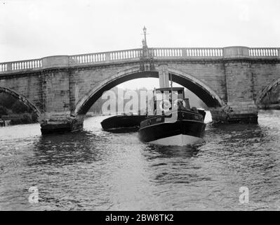 L'Association des maîtres Lightermen et des propriétaires de barges a déposé une demande de réparation du pont Richmond sur la Tamise à Londres. Les photos montrent un remorqueur remorquant une barge chargée sous le pont de Richmond . 1936 26 octobre 1936 Banque D'Images