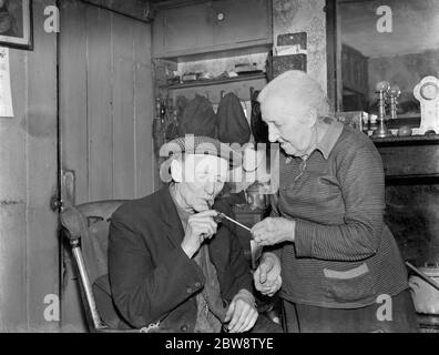 Mme Hoskins utilisant un raccord à la lumière MR Hoskins fumant pipe . 1938 . Banque D'Images