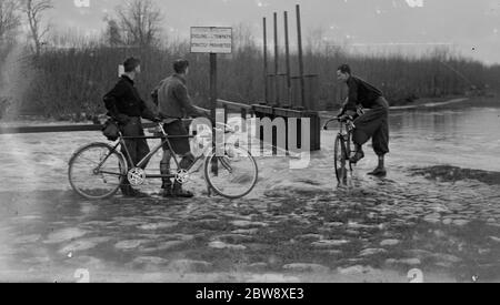 Les cyclistes regardent les niveaux d'eau élevés et les inondations au niveau de la rivière à Yalding dans le Kent . 1936 Banque D'Images