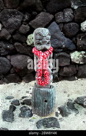 Le tiki ancien se dresse à la plage du parc historique national de Puuhonua o Honaunau sur la Grande île d'Hawaï. Un lei de plumeria rose a été l Banque D'Images