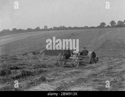 Les agriculteurs utilisant un nouveau tracteur tracent une machine de fabrication de foin sur un champ à Farningham , Kent . 16 juin 1937 Banque D'Images