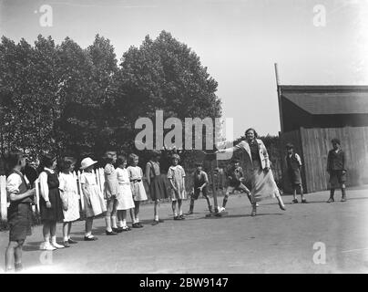 Une femme jouant du stoolball avec des enfants à Hartley , Kent . 1937 Banque D'Images