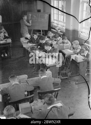 Enfants à l'école à Sidcup , Kent , pendant la guerre . Ici, ils sont dans une leçon de dessin avec leurs masques à gaz à portée de main en cas de bombardement . 1939 Banque D'Images