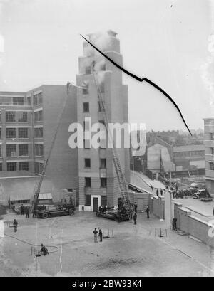 Un exposition de la brigade de pompiers de Londres à Lambeth , Londres. Les pompiers utilisent des échelles d'extension pour accéder et de tuyau aux fenêtres de l'étage supérieur d'un grand bâtiment pendant la démonstration . 1939 Banque D'Images