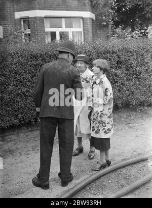 Des pompiers répondent à un incendie à Chislehurst , Kent . Un policier parle à Mme Evelyn Simpson . 1939 Banque D'Images