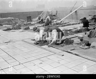 Travailleurs de Val de travers Asphalt Limited , une entreprise de pavage , travaillant sur un toit à Greenwich , Londres . 1938 Banque D'Images