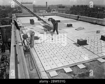 Des travailleurs de Val de travers Asphalt Limited , une entreprise de pavage , travaillant sur le revêtement du toit de l'hôpital juif de Londres à Stepney Green . 1938 Banque D'Images