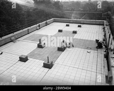 Des travailleurs de Val de travers Asphalt Limited , une entreprise de pavage , travaillant sur le revêtement du toit de l'hôpital juif de Londres à Stepney Green . 1938 Banque D'Images