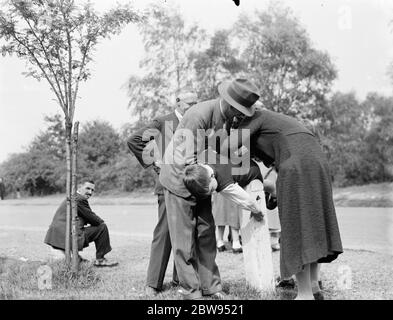 ' UN point dans le temps permet de gagner neuf '. Une mère coudre un petit trou sur son pantalon pour garçons . 1936 Banque D'Images