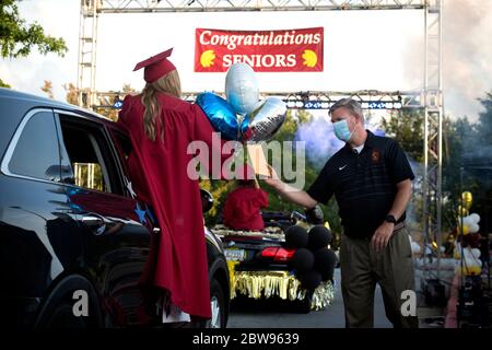 Marietta, GA, États-Unis. 29 mai 2020. Un senior de l'école secondaire Lassiter au nord d'Atlanta, reçoit son diplôme du directeur masqué Dr Chris Richie, dans un défilé de centaines d'élèves autour du terrain de l'école. La parade utilisait des mesures de distanciation sociale au lieu de la marche plus typique de l'auditorium en reconnaissance de la menace d'infecter d'autres personnes avec le virus Covid-19. Crédit : Robin Rayne/ZUMA Wire/Alay Live News Banque D'Images