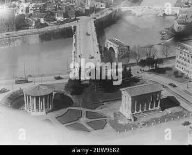 Le visage changeant de Rome . Sous le régime de fer de Mussolini, de nombreuses améliorations publiques sont en cours dans les anciens bâtiments de Rome , rénovés et aménagés dans les jardins publics . Une vue de certaines des améliorations de l'air montrant le nouveau pont Tibur avec les ruines de l'ancien Ponte Rotto , le pont immortalisé par Horatio Cocles , le héros romain légendaire de Lord Macaulay , Qui a glorieusement tenu ce pont avec deux camarades contre l'Armée Etrusque au sixième siècle jusqu'à ce que les citoyens le tailler et ainsi sauvé Rome . Sur la gauche se trouve le Temple de Vesta , la Déesse du coeur Banque D'Images