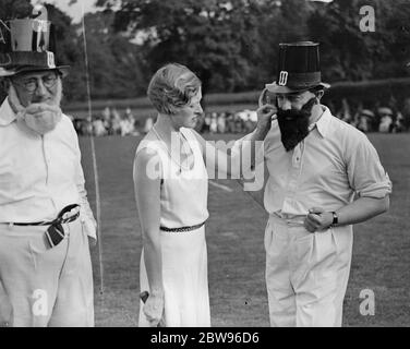 Auteurs contre actrices au cricket . Une équipe d'auteurs sous le chapelure de M. J B sacerdotal , et une équipe d'actrices sous le chapelure de Mlle Gladys Cooper , Rencontré dans un match de cricket à l'aide du groupe North St Pancras du groupe St Pancras de la St Pancras House Improvement Society dans les beaux jardins de la résidence de Mme Clarence Gasque à Hampstead , Londres . Tous les auteurs portaient de fausses barbes . Mlle Gladys Cooper ajustant la barbe sacerdotale de M. J B avant le match . 14 juillet 1932 Banque D'Images