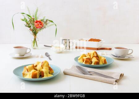 Petits pains aux levures avec zabaglione ou crème de vanille, ou aubergines, délicieux dessert sucré ou plat principal. Fond de table en bois blanc. Banque D'Images