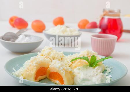 Boulettes de fruits farcies aux abricots, saupoudrées de fromage cottage et de sucre, recouvertes de beurre fondu, de crème fraîche et de zeste de lime râpé Banque D'Images