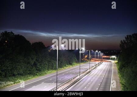 West Bromwich, West Midlands, 31 mai 2020. Vue depuis l'autoroute M5 depuis West Bromwich, vers Walsall avec de rares nuages Noctilucent illuminés dans le ciel nocturne. Les phénomènes fragiles de type nuage ne se forment que dans la haute atmosphère de la Terre. Contrairement aux nuages inférieurs qui sont associés au temps, ces nuages se forment très haut, à environ 85,300 mètres (53 milles) au-dessus de la surface de la Terre, dans la mésosphère. Ils sont probablement faits de cristaux d'eau ou de glace congelés et ne sont visibles que pendant le crépuscule astronomique. Le mot Noctilucent signifie en gros «nuit brillant» en latin. Ce sont le plus haut clou Banque D'Images