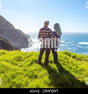 États-Unis, Californie, Big sur, couple de personnes âgées regardant l'océan depuis la falaise herbeuse Banque D'Images