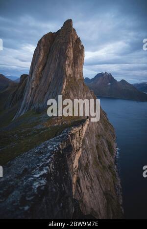 Norvège, Senja, Homme assis sur le bord de la falaise près de la montagne de Seglas Banque D'Images