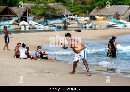 Un homme aime frapper une balle tout en jouant au cricket sur la plage de sable de la baie d'Arugam, sur la côte est du Sri Lanka. Banque D'Images