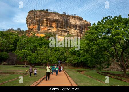 Les visiteurs de la forteresse de Sigiriya Rock au Sri Lanka marchent le long d'un chemin à travers le jardin royal en fin d'après-midi. Banque D'Images