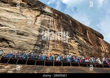 Une foule de personnes se déplaçant le long d'un passage sur la forteresse du Rocher Sigiriya, dans le centre du Sri Lanka. Ils sont à mi-chemin du sommet du Sigiriya Rock. Banque D'Images