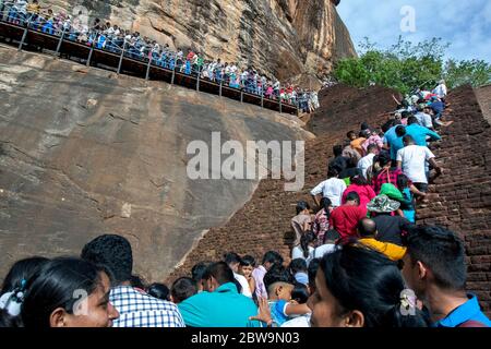 Une foule de personnes escalades l'ancien escalier en briques depuis les jardins royaux jusqu'à la forteresse de Sigiriya Rock dans le centre du Sri Lanka. Banque D'Images