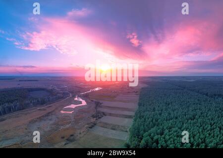 Paysage rural de printemps. Le village le soir. Oeil d'oiseau. Vue panoramique sur le village, les champs, la forêt de pins et la rivière au coucher du soleil. Panorama Banque D'Images