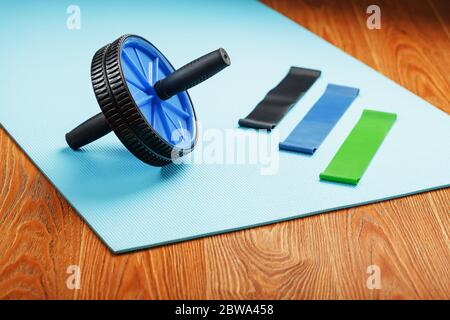 Ensemble pour le sport, rouleau bleu pour les muscles abs, bandes élastiques pour le fitness sur un tapis d'entraînement bleu. Banque D'Images