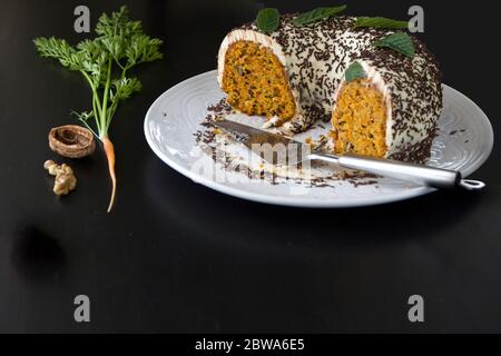 Gâteau de carottes maison sur un grand plat blanc sur fond sombre. Mise au point sélective, espace de copie Banque D'Images