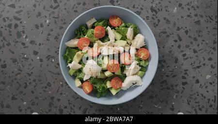 Salade vue de dessus avec tomates, avocat, mozzarella et feuilles de kale dans un bol en céramique bleu sur fond de béton Banque D'Images