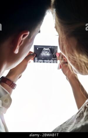 Homme et femme enceinte tenant une photo échographique dans leurs mains Banque D'Images