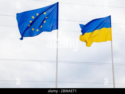 Le drapeau de l'Union européenne et de l'Ukraine flotte sur le mât. Drapeaux de l'Europe. Banque D'Images