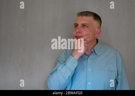Portrait d'un homme d'âge moyen touchant son visage avec la main. 40 ans homme ne regarde pas la caméra. Chemise d'affaires bleue habillée. Penser face et calme emoti Banque D'Images