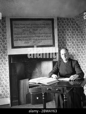 A Olney, dans le Buckinghamshire , le révérend M H Beauchamp ( vicaire de l'église Saint-Pierre et Saint-Paul ), dans l'étude de John Newton au presbytère , où ce dernier a écrit ses célèbres hymnes . 1926 Banque D'Images