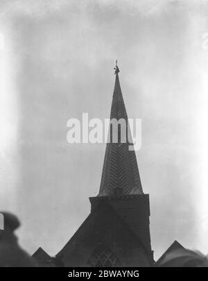 M. Ager , le steeplejack , au sommet de la flèche de l'église de Godalming , récupère un mouchoir attaché à la girouette par un de ses employés . 19 juin 1921 Banque D'Images