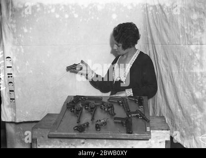 Au RKO Cinema Theatre , Leicester Square , Londres , une collection d'armes de gangster américaines est exposée . Une collection des révoltes les plus modernes - celles du plus grand type sont utilisées par la police mais les racketeurs favorisent la plus petite arme . Le particulier qui est utilisé principalement par les gangsters est le double barreled Derringer , qui est tenu par la fille . Ce vêtement est généralement porté dans la poche du gilet mais si le racketeer souhaite porter un plus grand pistolet, il est invariablement porté dans un étui sous le puits du bras gauche . 21 octobre 1931 Banque D'Images