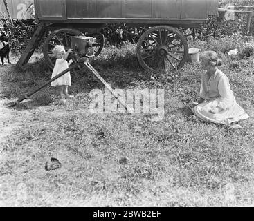 Deux familles ne peuvent pas trouver d'hébergement à Londres, ont loué une caravane et des tentes et sont campées sur la rive de la rivière à Staines . Bébé intéressé par la caméra de cinéma 13 août 1919 Banque D'Images