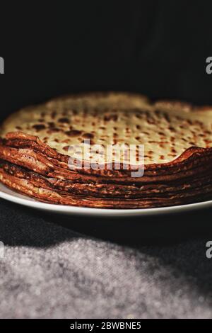 Fines crêpes, crêpes ou blinis sur ardoise isolée sur fond noir, savoureux petit déjeuner Banque D'Images