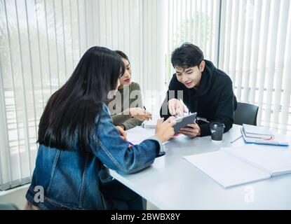 Les étudiants asiatiques lisent des livres et utilisent des tablettes numériques pour trouver des informations pour le travail et les études en ligne Banque D'Images