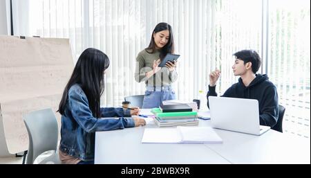 Les étudiants asiatiques lisent des livres et utilisent des tablettes numériques pour trouver des informations pour le travail et les études en ligne Banque D'Images