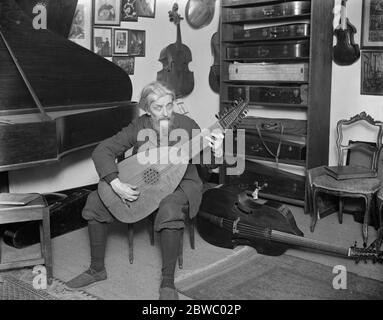 Préparation au festival Haslemere de musique de chambre ancienne . Famille célèbre qui font des instruments de temps vieux . M. Arnold Dolmetsch dans sa salle de musique . Il est vu jouer un luth . 23 janvier 1925 Banque D'Images