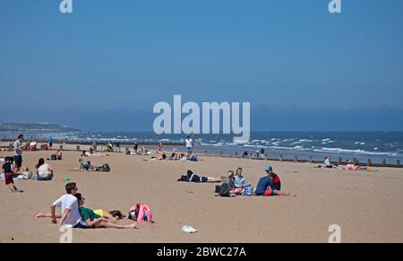 Portobello, Édimbourg, Écosse, Royaume-Uni. 31 mai 2020. Ensoleillé mais venteux avec 14 degrés centigrade, et ENE à 20 km/h et des rafales de 38 km/h, beaucoup préféraient rester enveloppé mais ceux qui couraient et s'asseyaient sur la plage semblaient avoir l'impression qu'il était assez chaud entre 12 heures et 13 heures. Les deux policiers de la promenade pourraient se rapporter pour ne pas avoir maintenu leur disance sociale les uns des autres. Une famille locale et trois jeunes garçons ont bravé le Firth of Forth pour s'amuser un peu dans la mer. Crédit : Arch White/Alamy Live News. Banque D'Images