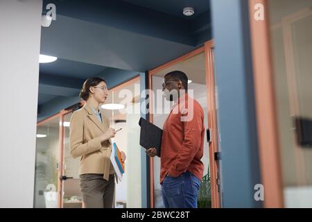 Portrait de deux personnes en voyage d'affaires contemporain avec vue latérale, dans un bureau coloré, dans un espace de photocopie Banque D'Images