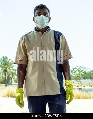 un jardiniste indien employé dans la grande mosquée sheikh zayed, portant des gants de main et un masque facial pendant le travail Banque D'Images